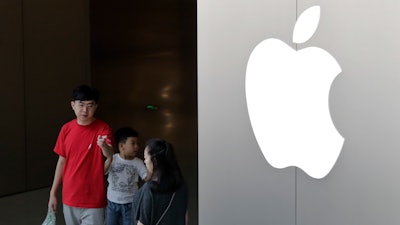 In this July 30, 2017, file photo, a Chinese family walks out of an Apple store in Beijing. Hundreds of workers protested Wednesday night, Oct. 18, 2017, over bonuses promised through labor brokers who recruited them to work at Jabil Inc.'s Green Point factory, an Apple supplier, in Wuxi city in southern China, according to witnesses.