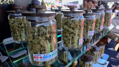 In this April 23, 2017, file photo, large jars of marijuana are on display for sale at the Cali Gold Genetics booth during the High Times Cannabis Cup in San Bernardino, Calif. California is kicking off recreational marijuana sales on Jan. 1, 2018, but there will be plenty of confusion as the new market takes shape. Some places are banning sales, while only a small number appear ready to issue licenses.