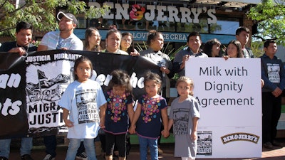 Children stand in front of a banner commemorating an agreement signed by ice cream maker Ben & Jerry's and immigrant farm workers, Tuesday, Oct. 3, 2017, in Burlington, Vt. The agreement promotes the rights of immigrant farm workers while paying more to the farmers who employ them. The company and the workers said it's the first agreement of its kind in the dairy industry.
