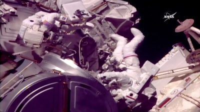 In this frame from NASA TV, Astronauts Mark Vande Hei and Randy Bresnik, right, emerge from the International Space Station on Tuesday, Oct. 10, 2017. The astronauts went out on a spacewalk to grease the robot arm's new hand.