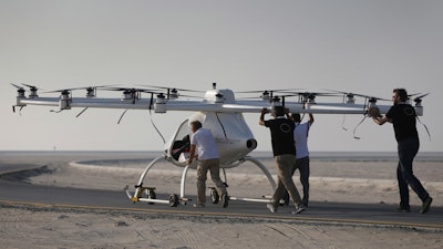 In this Sept. 26, 2017 photo, a Volocopter prototype is being pushed by their operators before it sets for a test fly in Dubai, United Arab Emirates, Tuesday, Sept. 26, 2017. Dubai is hoping to one day have flying, pilotless taxis darting among its skyscrapers. Just this week, the city-state in the United Arab Emirates hosted crews from the German company Volocopter, which had an electric, battery-powered two-seat prototype take off and land. Dubai hopes to have rules in place in the next five years to be ready for having the aircraft regularly flying through its skies.