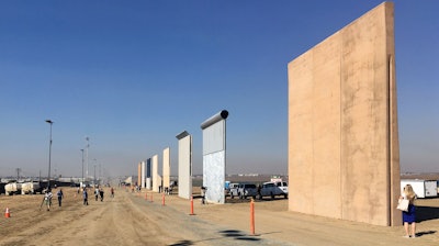 People look at prototypes of a border wall Thursday, Oct. 26, 2017, in San Diego. Contractors have completed eight prototypes of President Donald Trump's proposed border wall with Mexico, triggering a period of rigorous testing to determine if they can repel sledgehammers, torches, pickaxes and battery-operated tools.