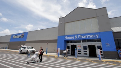 In this Thursday, June 1, 2017, photo, customers walk out of a Walmart store in Hialeah Gardens, Fla. Walmart is expected to provide an update about its expansion plans and issue an outlook for revenue and earnings at its annual shareholder meeting, Tuesday, Oct. 10, 2017.