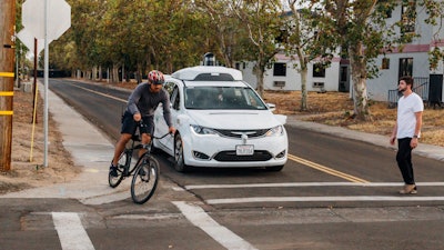This Sunday, Oct. 29, 2017, photo provided by Waymo shows a Chrysler Pacifica minivan equipped with Waymo's self-driving car technology, being tested with the company's employees as a biker and a pedestrian at Waymo's facility in Atwater, Calif. Waymo, hatched from a Google project started eight years ago, showed off its progress Monday during a rare peek at a closely guarded testing facility located 120 miles southeast of San Francisco where its robots complete their equivalent to driver's education.