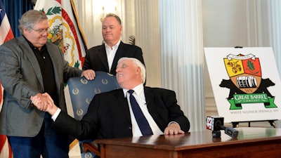 West Virginia Gov. Jim Justice, center, shakes hands with West Virginia Great Barrel Co. managing partners Tom Crabtree, left, and Philip Cornett following the announcement Thursday, Oct. 19, 2017, in Charleston W.Va., that a barrel-making facility will be constructed in White Sulphur Springs. The company that makes whiskey barrels out of white oak wood has been born from efforts to rebuild a devastated West Virginia community following deadly floods.