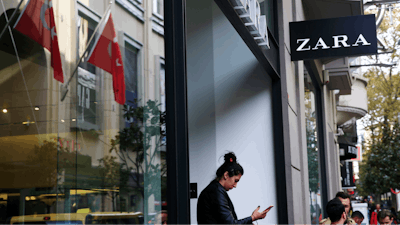 In this Friday, Nov. 3, 2017 file photo, a shopper exits a branch of fashion retailer Zara in an upscale Istanbul neighbourhood. Zara said Monday, Nov. 6, 2017, it is working on establishing a 'hardship fund' to help a group of Turkish workers who were left unpaid when an outsource factory closed down. The workers went into Zara shops in Istanbul, leaving tags inside garments that read: 'I made this item you are going to buy, but I didn't get paid for it.'