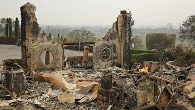 In this Oct. 10, 2017 file photo, the remains of the Signorello Estate winery continue to smolder in Napa, Calif. A month after deadly wildfires swept through California's famed wine country. Lost in the fire was the Napa winery’s signature stone hospitality building. A kitchen, corporate offices, a wine lab and the home of owner Ray Signorello Jr. also were destroyed.