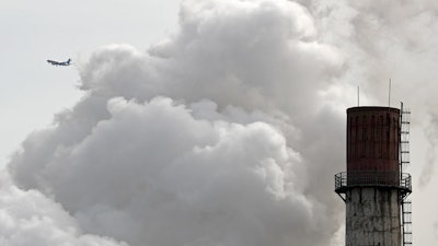 In this Feb. 28, 2017 file photo, a passenger airplane flies behind steam and white smoke emitted from a coal-fired power plant in Beijing. On Monday, Nov. 13, 2017, scientists projected that global carbon pollution has risen in 2017 after three straight years when the heat-trapping gas didn’t go up at all.