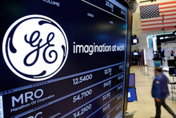In this Monday, June 12, 2017, file photo, the General Electric logo appears above a trading post on the floor of the New York Stock Exchange. GE said Monday, Nov. 13, 2017, that it is slashing its quarterly dividend in half with investors gathering in Boston, where Chairman and CEO John Flannery is expected to lay out significant changes for the U.S. company.
