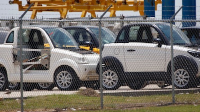 In this June 13, 2016, file photo, production cars are parked outside the GreenTech Automotive manufacturing plant in Robinsonville, Miss. A group of Chinese investors is suing Virginia Gov. Terry McAuliffe over his past work for troubled electric car maker GreenTech Automotive. The investors filed a lawsuit in Fairfax County last week accusing McAuliffe and Hillary Clinton's brother Anthony Rodham of milking their political connections to perpetuate a $120 million scam.