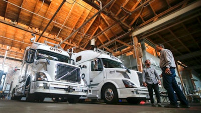 In this Thursday, Aug. 18, 2016, file photo, employees stand next to self-driving, big-rig trucks during a demonstration at the Otto headquarters, in San Francisco. Uber's self-driving startup Otto developed technology allowing big rigs to drive themselves. After taking millions of factory jobs, robots could be coming for a new class of worker: people who drive for a living.