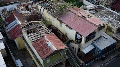 In this Nov. 15, 2017 photo, some roofs damaged by the whip of Hurricane Maria are still exposed to rainy weather conditions, in San Juan, Puerto Rico. A newly created Florida company with an unproven record won more than $30 million in contracts from the Federal Emergency Management Agency to provide emergency tarps and plastic sheeting for repairs to hurricane victims in Puerto Rico. Bronze Star LLC never delivered those urgently needed supplies, which even months later remain in demand on the island.