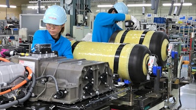 In this Oct. 30, 2017, photo, workers of Toyota Motor Corp. set hydrogen-stored tanks, in yellow, to be placed into a Mirai fuel cell vehicle at the automaker's Motomachi plant, in Toyota, western Japan. Toyota is banking on a futuristic “electrification” auto technology called hydrogen fuel cells for its zero-emissions option. The Associated Press got a tour of Toyota’s Motomachi plant that assembles the Mirai fuel cell vehicle.