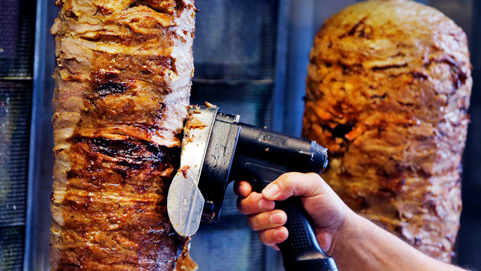 In this Thursday, Nov. 30, 2017 file photo, a man slices cuts of meat from a rotisserie Doner spit inside a Doner restaurant cafe in Frankfurt, Germany. The European Parliament narrowly defeated plans to ban an additive that is considered key in industrial meats for the popular doner kebab. Needing an absolute majority of at least 376 votes for a ban on phosphates, the legislature fell 3 votes short on Wednesday, Dec. 13, 2017.