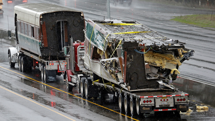 Two damaged train cars sit on flatbed trailers after being taken from the scene of an Amtrak train crash onto Interstate 5 a day earlier Tuesday, Dec. 19, 2017, in DuPont, Wash. Federal investigators say they don't yet know why the Amtrak train was traveling 50 mph over the speed limit when it derailed Monday south of Seattle.