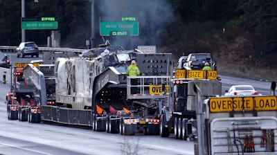 The engine from an Amtrak train that crashed onto Interstate 5 on Monday, is transported away from the scene, Wednesday, Dec. 20, 2017, in DuPont, Wash. Federal investigators in the deadly train wreck want to know whether the engineer was distracted by a second person in his cab as his train hurtled into a curve at more than twice the speed limit. The train took a 30 mph curve at 80 mph and plunged off an overpass, sending rail cars plummeting onto a busy highway south of Seattle.