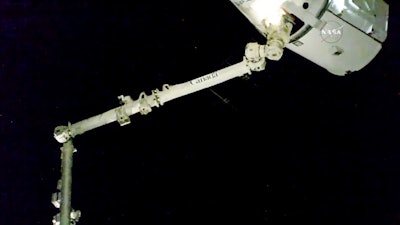 In this image taken from NASA Television, the robotic arm reaches out and captures the SpaceX Dragon cargo spacecraft for docking to the International Space Station.