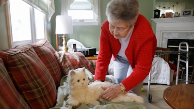 Mary Derr holds her robot cat she calls 'Buddy' as she talks to it in her home. Derr has mild dementia, and her daughter purchased a 'Joy for All' robotic cat earlier this year to keep her mother company.