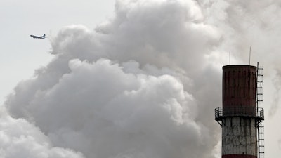 In this file photo taken Tuesday, Feb. 28, 2017, a passenger airliner flies past steam and white smoke emitted from China Huaneng Group's Beijing power plant that was the last coal-fired plant to shut down on March 18, 2017, as the Chinese capital convert to clean energy like thermal power. Chinese authorities have commandeered supplies of natural gas to heat homes, disrupting supplies to industry, after efforts to clear smog-choked air by banning coal use led to energy shortages in frigid weather.