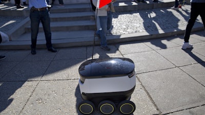 In this Feb. 20, 2017, file photo, a six-wheeled ground delivery robot, from Starship Technologies, shares the sidewalk with pedestrians at DuPont Circle in Washington, D.C. Delivery robots in San Francisco will need permits before they can roam city sidewalks under legislation approved by supervisors on Tuesday, Dec. 5, 2017.