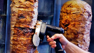 In this Thursday, Nov. 30, 2017 file photo, a man slices cuts of meat from a rotisserie Doner spit inside a Doner restaurant cafe in Frankfurt, Germany. The European Parliament narrowly defeated plans to ban an additive that is considered key in industrial meats for the popular doner kebab. Needing an absolute majority of at least 376 votes for a ban on phosphates, the legislature fell 3 votes short on Wednesday, Dec. 13, 2017.