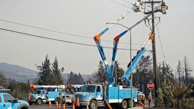 In this Oct. 11, 2017 file photo, a Pacific Gas & Electric crew works at restoring power along the Old Redwood Highway in Santa Rosa, Calif. California utility Pacific Gas & Electric Co. is suspending dividend payments to shareholders out of concern for any financial liability in Northern California wildfires. The utility's board announced the move in a statement Wednesday, Dec. 20, 2017.