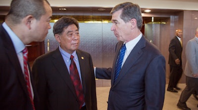 In a photo provided by the North Carolina Governors Office, North Carolina Gov. Roy Cooper, right, speaks to Triangle Tire Chairman Ding Yuhua, center, and his translator Tuesday, Dec. 19, 2017, at Edgecombe Community College in Tarboro, N.C., after the company announced plans to build a tire plant that would eventually employ 800 workers and produce 6 million tires a year.