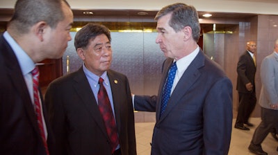 In a photo provided by the North Carolina Governors Office, North Carolina Gov. Roy Cooper, right, speaks to Triangle Tire Chairman Ding Yuhua, center, and his translator Tuesday, Dec. 19, 2017, at Edgecombe Community College in Tarboro, N.C., after the company announced plans to build a tire plant that would eventually employ 800 workers and produce 6 million tires a year.