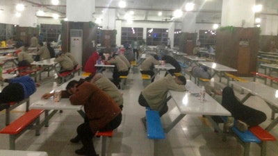 In this photo taken in Oct. 2017 and provided to the Associated Press by China Labor Watch, workers rest at night in a cafeteria at a Catcher Technologies factory in Suqian in eastern China's Jiangsu province. An Apple Inc. supplier in eastern China on Wednesday denied allegations by a New York rights group that its workers toil for ten-hour shifts in loud, polluted conditions, without proper overtime pay or adequate safety protections to make MacBook and iPhone parts, before returning to filthy dormitories with cold showers. Apple also said it sent an investigative team to Suqian to interview over 150 workers but 'found no evidence that Catcher was violating our standards.'