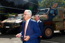 Australia Prime Minister Malcolm Turnbull walks in front of military trucks during a visit to Thales Underwater Systems in Sydney, Monday, Jan. 29, 2018. The government announced a new strategy to boost Australia into the ranks of the top 10 defense industry exporting countries within a decade through arms sales to liked-minded nations and with safeguards to keep weapons out of the hands of rogue regimes.