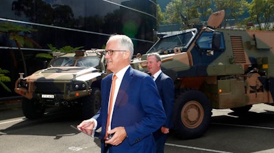Australia Prime Minister Malcolm Turnbull walks in front of military trucks during a visit to Thales Underwater Systems in Sydney, Monday, Jan. 29, 2018. The government announced a new strategy to boost Australia into the ranks of the top 10 defense industry exporting countries within a decade through arms sales to liked-minded nations and with safeguards to keep weapons out of the hands of rogue regimes.