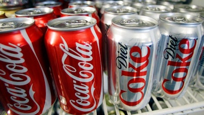 In this March 17, 2011, file photo, cans of Coca-Cola and Diet Coke sit in a cooler in Anne's Deli in Portland, Ore. The Coca-Cola Co. plans to help collect and recycle a bottle or can for every one that it sells by 2030. The beverage company is also working on making all of its packaging 100 percent recyclable worldwide. Coca-Cola said Friday, Jan. 19, 2018, that it's creating bottles with more recycled content by developing plant-based resins.