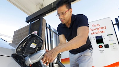 In this Thursday, Sept. 17, 2015 file photo, Darshan Brahmbhatt, plugs a charger into his electric vehicle at the Sacramento Municipal Utility District charging station in Sacramento, Calif. Calif., Gov Jerry Brown, on Friday, Jan. 26, 2018, issued and executive order outlining a plan to put 5 million zero-emission vehicles on California's roads by 2030.