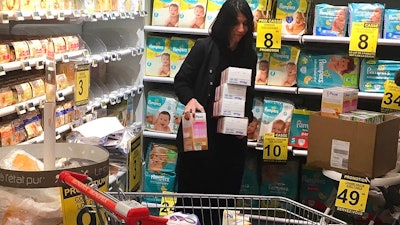 Pharmacist Deborah Cohen removes boxes of baby milk in Paris, Thursday, Dec. 21, 2017. A tainted baby milk scandal affecting some 30 countries is growing, as French dairy giant Lactalis recalled millions more products globally because of fears of salmonella contamination. Lactalis had already recalled several million baby milk products earlier this month.