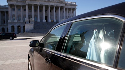 Extra shirts hang inside of a senator's vehicle as the Capitol dome is reflected on Capitol Hill as a bitterly-divided Congress hurtles toward a government shutdown this weekend, Friday, Jan. 19, 2018, in Washington.