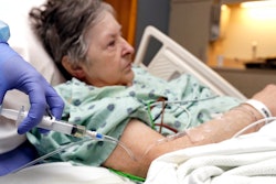 In this Monday, Jan. 8, 2018, photo, a nurse administers an I.V. push of antibiotics to Alice McDonald at ProMedica Toledo Hospital in Toledo, Ohio. A nasty flu season is hitting U.S. hospitals already scrambling to maintain patient care amid severe shortages of crucial sterile fluids, particularly saline solution needed to administer I.V. medicines and rehydrate patients.