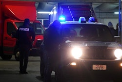 Police officers stand next to trucks parked in a garage during an operation aiming to break up a Chinese transport mafia, in Prato, Italy, Jan. 18, 2018. Anti-mafia prosecutors in Italy say they have broken up a Chinese organized crime ring that used money from criminal activities to force their way into the transport sector, not only in Italy but elsewhere in Europe.