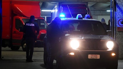 Police officers stand next to trucks parked in a garage during an operation aiming to break up a Chinese transport mafia, in Prato, Italy, Jan. 18, 2018. Anti-mafia prosecutors in Italy say they have broken up a Chinese organized crime ring that used money from criminal activities to force their way into the transport sector, not only in Italy but elsewhere in Europe.