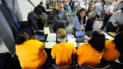 In this Wednesday, Aug. 2, 2017, file photo, job candidates are processed during a job fair at the Amazon fulfillment center in Robbinsville Township, N.J. On Friday, Jan. 5, 2018, the U.S. government issues the December jobs report.
