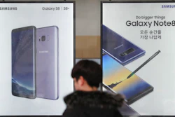 In this Monday, Jan. 8, 2018, photo, a man walks by advertisements of Samsung Electronics' smartphone at its shop in Seoul, South Korea.