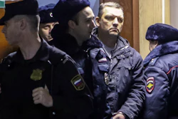 Ilya Averyanov, the former owner of a Moscow candy factory, is escorted in a court room in Moscow, Russia, Thursday, Dec. 28, 2017. Averyanov, the former owner of a Moscow candy factory, argued with its new owner and then fired a hunting rifle, killing a security guard and wounding three other people. The court ordered Thursday to keep him in jail for two months pending investigation.