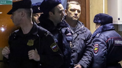 Ilya Averyanov, the former owner of a Moscow candy factory, is escorted in a court room in Moscow, Russia, Thursday, Dec. 28, 2017. Averyanov, the former owner of a Moscow candy factory, argued with its new owner and then fired a hunting rifle, killing a security guard and wounding three other people. The court ordered Thursday to keep him in jail for two months pending investigation.