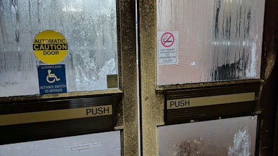 In this Tuesday, Jan. 2, 2018, photo provided by Rebecca Miller, condensation covers an exterior door at Holland Hall on the Tennessee State University campus in Nashville, Tenn. Many office workers find they still have to brave the cold even after they escape the frigid outdoors during the extremely cold winter weather. Miller, an academic adviser at the school, wears sweaters, a scarf, ear coverings, gloves and a blanket over her lap while she works in the building.