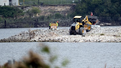 In this Sept. 13, 2017, file photo, workers are shown at San Jacinto River Waste Pits near the Interstate 10 bridge over the river in Channelview, Texas. The Environmental Protection Agency says an unknown amount of a dangerous chemical linked to birth defects and cancer may have washed downriver from a Houston-area Superfund site during the flooding from Hurricane Harvey.
