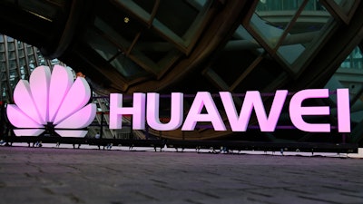 In this May 26, 2016 file photo, people walk past an illuminated logo for Huawei at a launch event for the Huawei MateBook in Beijing. A Chinese court notice says homegrown tech giant Huawei has won a patent infringement lawsuit against South Korea smartphone rival Samsung. The notice released Thursday, Jan. 11, 2018 said the court ruled in the Chinese company’s favor over two patents involving fourth generation phone technology.