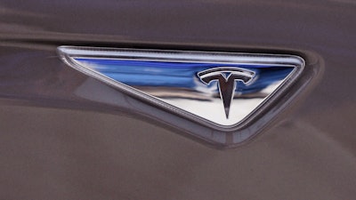 This April 7, 2015 file photo shows the Tesla logo on the new Tesla Model S 70D during a test drive in Detroit. Tesla says it’s put together a 10-year compensation package for CEO Elon Musk that pays him based on certain market cap and operational milestones he hits - otherwise he gets nothing. The electric vehicle maker says Tuesday, Jan. 23, 2018, its market cap would have to grow to $650B for Musk to fully vest.