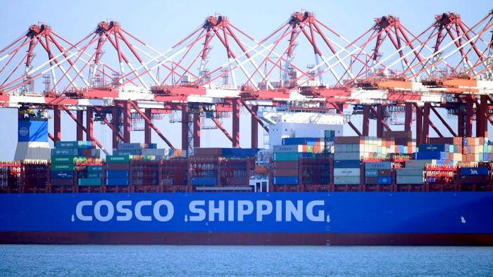 In this Jan. 12, 2018 photo, trucks move containers are loaded onto a ship at a port in Qingdao in eastern China's Shandong province. China's export growth accelerated in January in a sign of resilient global demand while imports surged as factories stocked up before closing for the two-week Lunar New Year holiday.