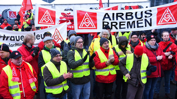 Airbus employees gather in front of the company in Bremen, northern Germany, during a strike in Bremen, Germany, Friday, Feb. 2, 2018. The union is seeking a 6-percent pay increase and the right to reduce work weeks to 28 hours for up to two years, with a guarantee that workers can return to regular hours.