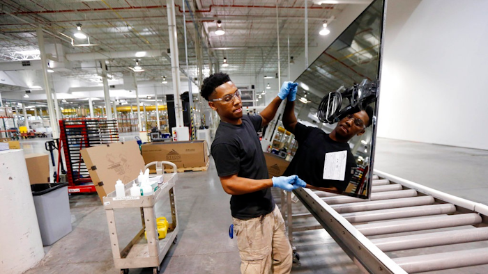 In this June 15, 2016, photo, Ricky Foster gingerly carries a completed solar panel to a shipping case after inspecting and cleaning its surface at Stion, a solar panel maker in Hattiesburg, Miss. On Thursday, Feb. 15, 2018, the Federal Reserve reports on U.S. industrial production for January.