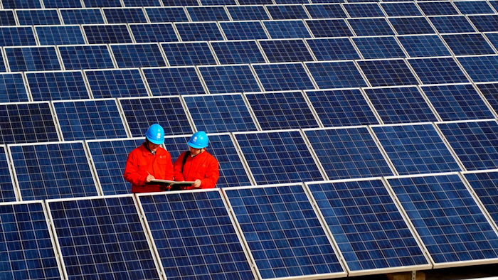 In this Feb. 7, 2012, file photo, workers check solar panels at a solar power station on a factory roof in Changxing in eastern China's Zhejiang province. One of China's biggest makers of solar panels said Tuesday, Feb. 6, 2018, that it will invest $309 million to expand manufacturing in India to guard against what it said is a rising threat of import controls in the United States and other markets.